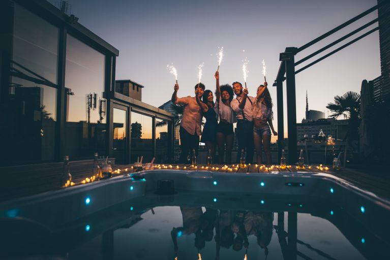 Group of friends having fun on the rooftop of a beautiful penthouse with a pool hot tub